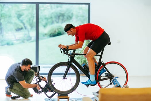 A cameraman filming an athlete riding a triathlon bike on a simulation machine in a modern living room. Training in pandemic conditions