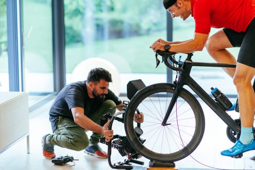 A cameraman filming an athlete riding a triathlon bike on a simulation machine in a modern living room. Training in pandemic conditions