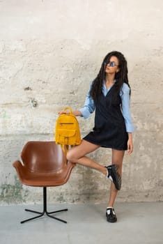 A fashionable model confidently showcasing a modern outfit while sporting a yellow backpack accessory