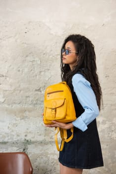 A fashionable model confidently showcasing a modern outfit while sporting a yellow backpack accessory