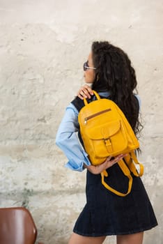 A fashionable model confidently showcasing a modern outfit while sporting a yellow backpack accessory