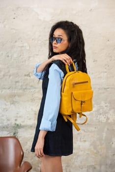 A fashionable model confidently showcasing a modern outfit while sporting a yellow backpack accessory
