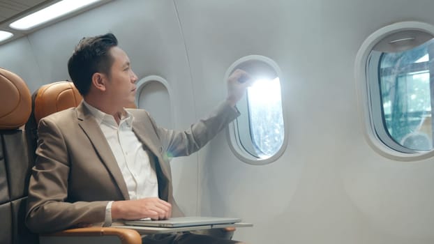 Professional Asian businessman working with notebook computer while sitting inside an airplane, business man working with laptop in aircraft cabin during his business travel