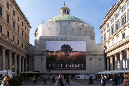 Milan, Italy - April, 08, 2025: Ralph Lauren billboard with countryside house ad in Milan Piazza San Babila. Pedestrians and architecture in daylight.