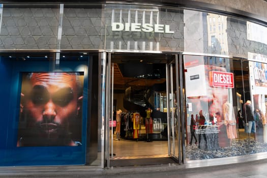 Milan, Italy - April, 08, 2025: Diesel fashion store entrance with illuminated signage, street-level view with interior display and branded visual screens.