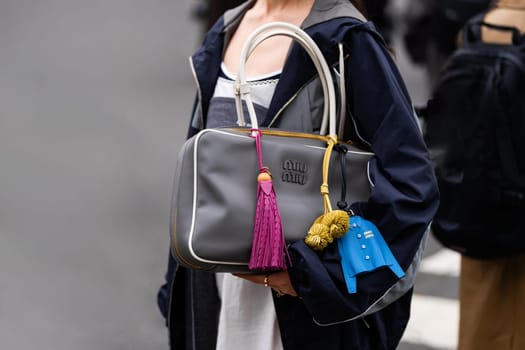 Paris, France - March 11, 2025: Gray Miu Miu leather top handle bag with colorful tassels and charm details. Street style outfit details.