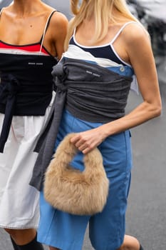 Paris, France - March 11, 2025: Woman wears tan fluffy faux fur Miu Miu handbag and layered sporty Miu Miu outfit. Street style outfit details.
