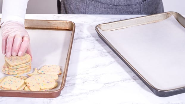 The sugar cookies, filled with sprinkles mixed into the dough, are carefully arranged with meticulous precision into a rustic brown paper box.