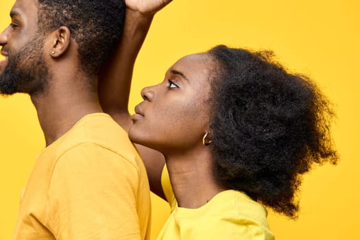 This vibrant image features a young Black couple with natural hairstyles, dressed in matching yellow outfits Set against a bright yellow background, the photo conveys emotions of love and connection