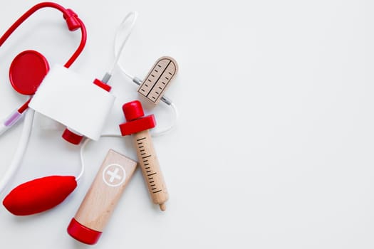 Colorful wooden toy doctor kit with stethoscope and syringe on white background.