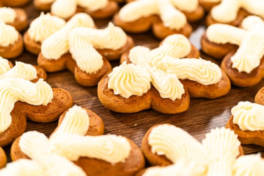 Making gingerbread man cookie sandwiches filled with eggnog buttercream, arrayed on a rustic wooden table, ideal for heartfelt Christmas gifting.