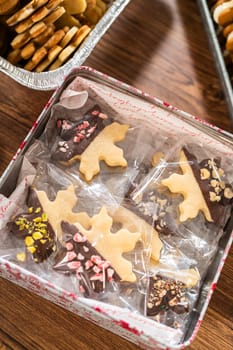 Lovingly homemade gingerbread and sugar cookies, half-dipped in rich chocolate, nestled in decorative Christmas tin boxes perfect for seasonal gifting.