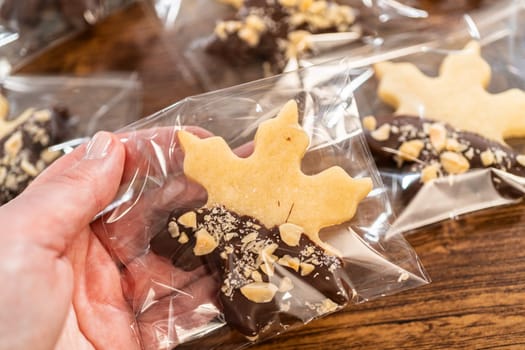 Carefully packaging Christmas cutout cookies, half-dipped in chocolate and presented in clear cellophane wrapping, perfect for festive gifting.