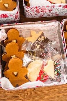 Lovingly homemade gingerbread and sugar cookies, half-dipped in rich chocolate, nestled in decorative Christmas tin boxes perfect for seasonal gifting.