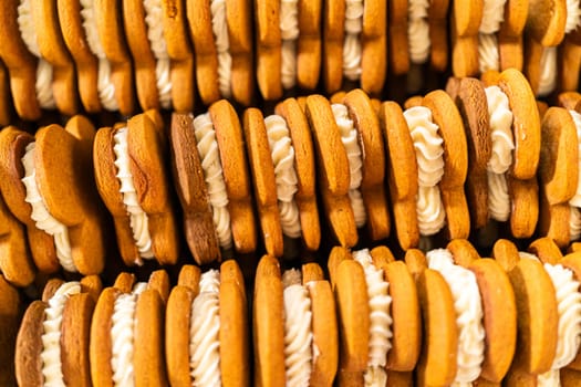 Making gingerbread man cookie sandwiches filled with eggnog buttercream, arrayed on a rustic wooden table, ideal for heartfelt Christmas gifting.
