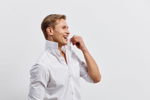 Smiling young caucasian man wear white shirt stand isolated on plain background look side profile with happy positive emotion for mental health and wellness concept. Casual lifestyle, hope and optimism feelings.
