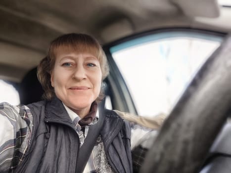 A blonde woman captures a cheerful selfie while driving, likely on a travel excursion during a sunny day.