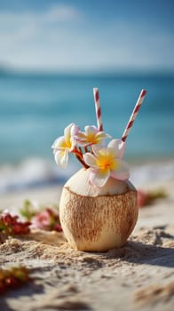 Tropical drink in a coconut with flowers and straws on a sunny beach.