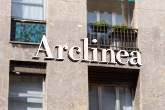 Milan, Italy - April, 08, 2025: Arclinea showroom logo reflected in glass with modern urban residential building background.