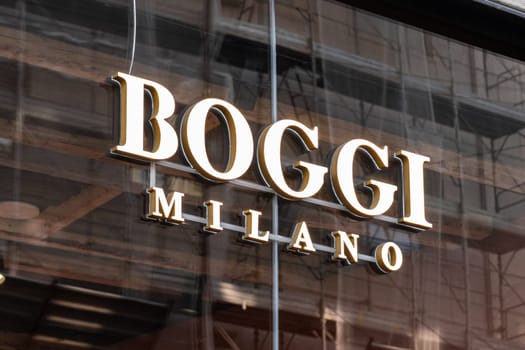 Milan, Italy - April, 08, 2025: Boggi Milano illuminated logo on storefront glass. Italian menswear brand display in city retail fashion district.