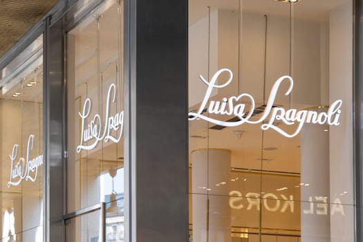 Milan, Italy - April, 08, 2025: Luisa Spagnoli store logo sign on glass facade. Elegant branding with script typography and modern retail reflection in Milan.