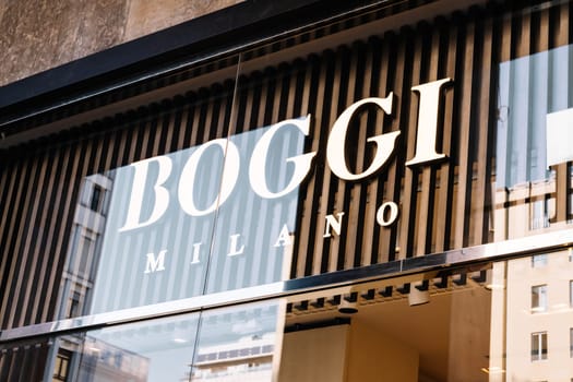 Milan, Italy - April, 08, 2025: Closeup of Boggi Milano store logo on vertical slatted facade. Luxury fashion storefront exterior in Milan, Italy. Reflective glass.