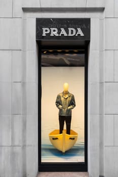 Milan, Italy - April, 08, 2025: Prada window display in Milan. Male mannequin in denim jacket stands inside yellow boat. High fashion storefront concept.