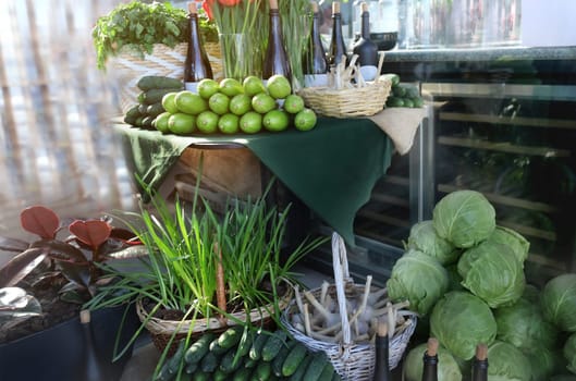 Market display case with fresh vegetables and wine. Fresh cucumbers, young cabbage, wine, greens and flowers, parsley, garlic. Healthy vegetarian ingredients for cooking.