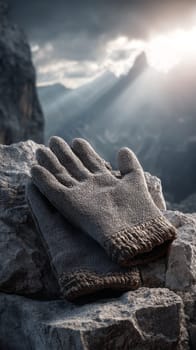 Grey gloves on rocky mountain with dramatic sunlight, symbolizing adventure.