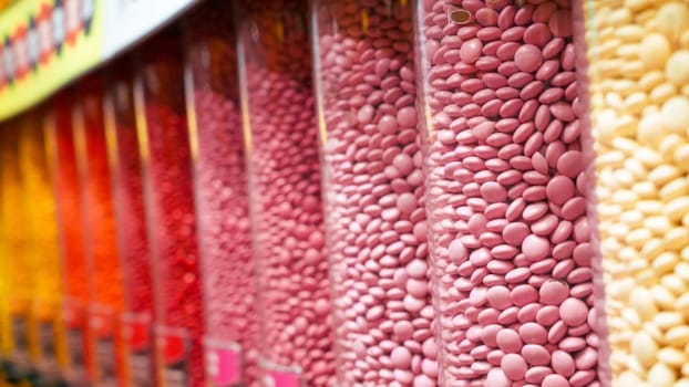 Colorful round candies displayed in clear plastic containers, arranged in a neat row. Perfect for backgrounds or illustrations related to the confectionery industry.