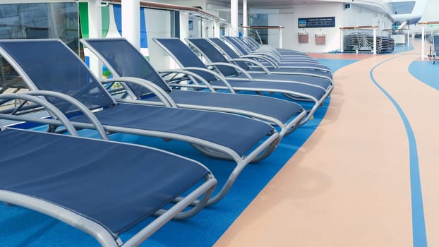 A serene view of blue deck chairs perfectly arranged in neat rows on a luxurious cruise ship deck. New York NY USA - 09.02.2024.