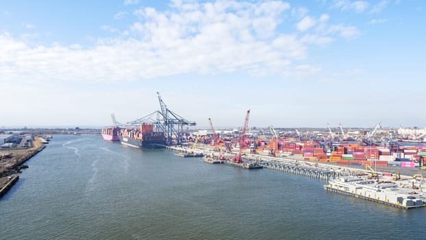 New York NY USA - 09.02.2024: Cargo containers stacked in a shipping yard near the sea with a city in the background.