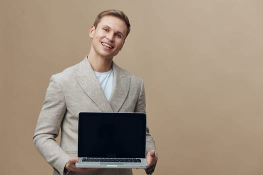 smiling happy young caucasian man hold laptop computer in hands wear casual jacket stand isolated on beige background digital nomad concept freelance work technology online communication