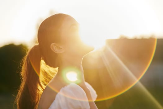 A serene young woman enjoying warm sunlight during summer, conveying feelings of peace and joy The glowing background enhances the overall beauty of the moment