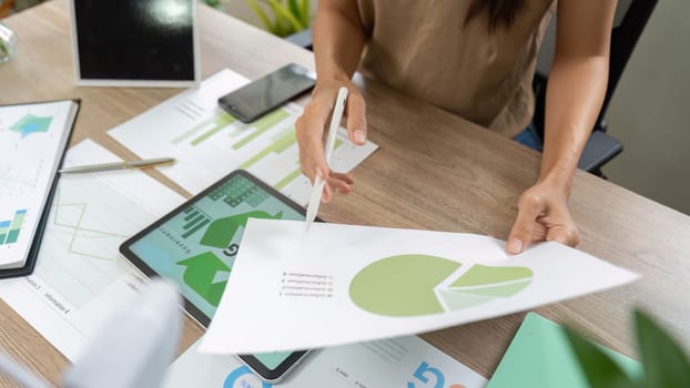 A focused woman conducting a sustainability assessment by analyzing data and charts related to environmental performance and ESG.
