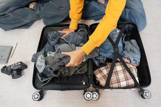 A young woman organizing her clothes into a suitcase while preparing for her travel adventure, showcasing excitement and anticipation.