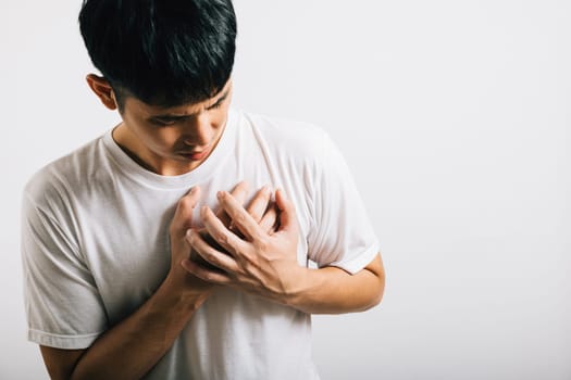 Portrait Asian young man holding his arms around his chest suffering because of a heart attack studio isolated white background, Happy lifestyle men chest pain health discomfort heart problems