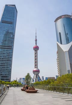Shanghai, China – 1 April 2025: View of the Oriental Pearl Tower and surrounding skyscrapers in Pudong with people relaxing on the pedestrian promenade