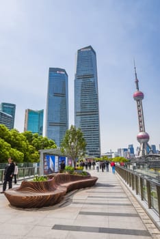 Shanghai, China - 1 April 2025: The pedestrian zone in Pudong showcases Shanghai's iconic skyline, featuring the Oriental Pearl Tower and modern designer benches, with locals and tourists enjoying a sunny day.