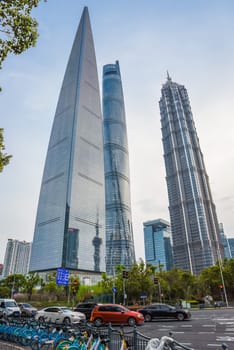 Shanghai, China - 1 April 2025: Shanghai Tower, Jinmao Tower and SWFC pierce the twilight sky as evening traffic flows below, with parked bicycles adding urban charm to this spring sunset scene in Pudong