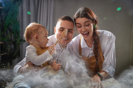 A family enjoys a fun cooking session, playfully covered in flour while engaging with their little ones in warm kitchen