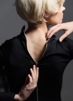 Stylish young model highlights the back of her black outfit with a zipper, exuding confidence and sophistication. Emphasizing modern fashion trends.