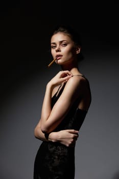 Stylish female model dressed in a sleek black gown, exuding confidence and allure, captured in low-key lighting to enhance the dramatic effect.