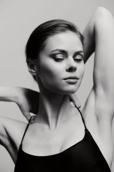 Black and white image of a poised female model, exuding grace and tranquility while playing with her hair. The minimalist background accentuates her features and the essence of modern beauty.
