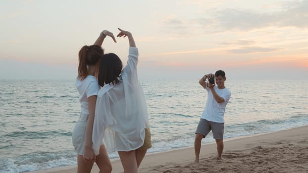 Happy friends smiling and posing taking photo from smartphone and having fun together on beach in holiday vacation time at sunset, Young Asian group woman and man in summer travel outdoor