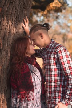 young couple in love walking and having fun in autumn park. they look at each other, against the background of autumn trees. concept of romance, falling in love, relaxation