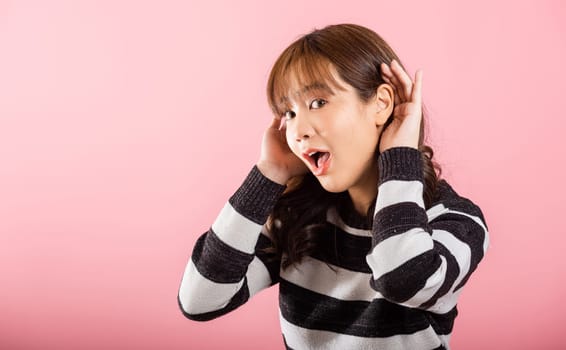 Asian portrait beautiful cute young woman teen smiling overhearing listening sound to gossip with attention with her hand on ear studio shot isolated on pink background with copy space hearing gesture