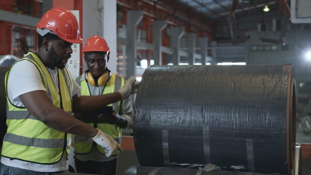 Engineer two worker man African black marking inspection on roll metal sheet before shipment in warehouse of Metal Sheet factory, Physical inventory count, checking stock industry