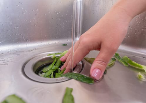 Recycling food scraps: fresh vegetable peels entering a garbage disposal system.