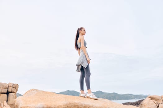 Fitness enthusiast showcases athletic wear while standing on rocks, embodying confidence and wellness in a tranquil outdoor setting, ideal for healthy lifestyle inspiration